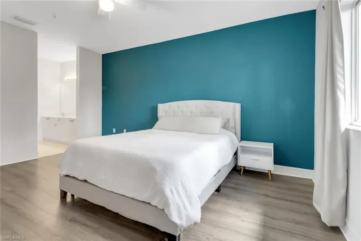 Bedroom featuring baseboards, wood finished floors, a ceiling fan, and connected bathroom