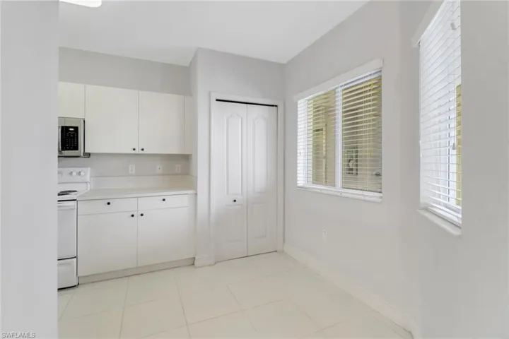 Kitchen with stainless steel microwave, electric stove, light countertops, and white cabinets