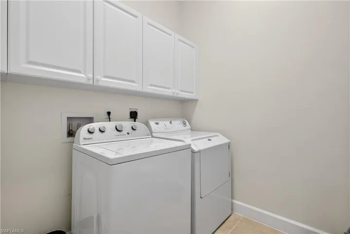 Laundry room with separate washer and dryer, cabinet space, and light tile patterned floors