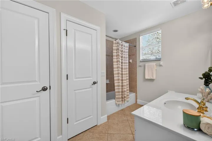 Full bathroom with vanity, light tile patterned floors, and shower / bathtub combination with curtain
