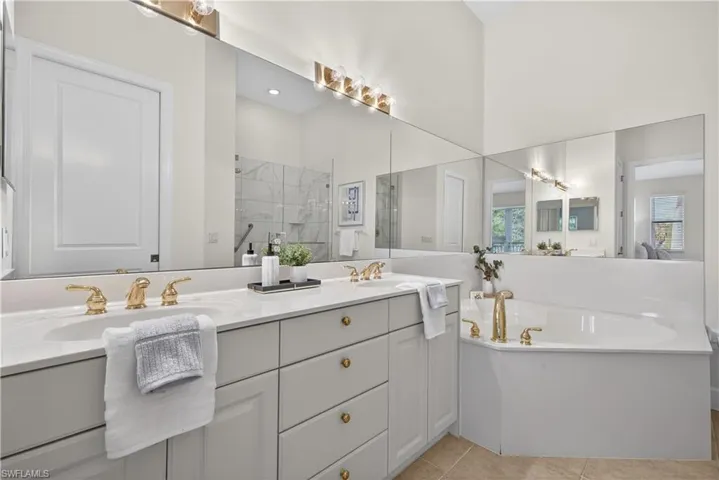Full bath with double vanity, a shower stall, a bath, and light tile patterned flooring