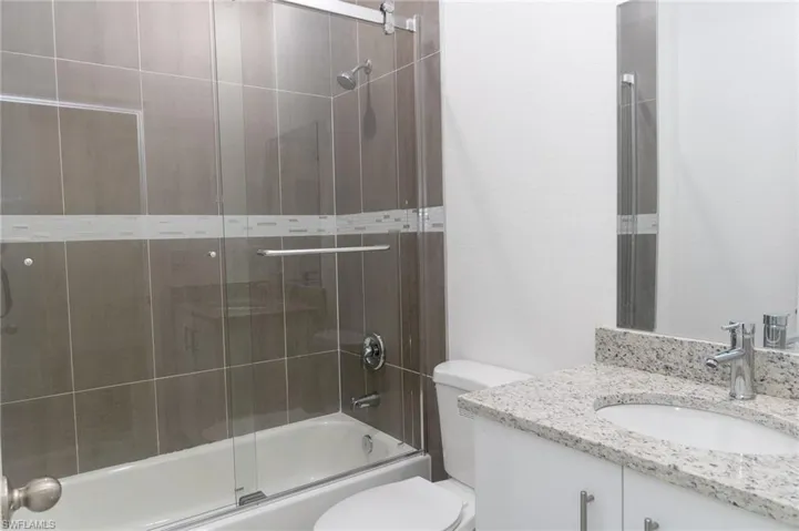 Full bathroom featuring enclosed tub / shower combo, vanity, and toilet