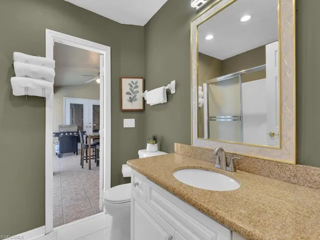 Bathroom with ceiling fan, walk in shower, tile patterned flooring, toilet, and vanity
