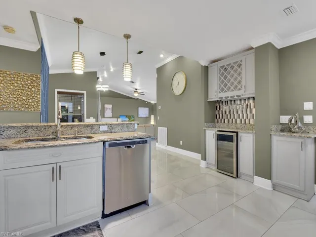 Kitchen with dishwasher, sink, wine cooler, vaulted ceiling, and white cabinetry