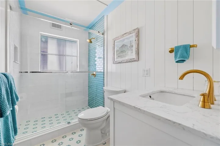 Bathroom featuring vanity, a shower with shower door, and toilet