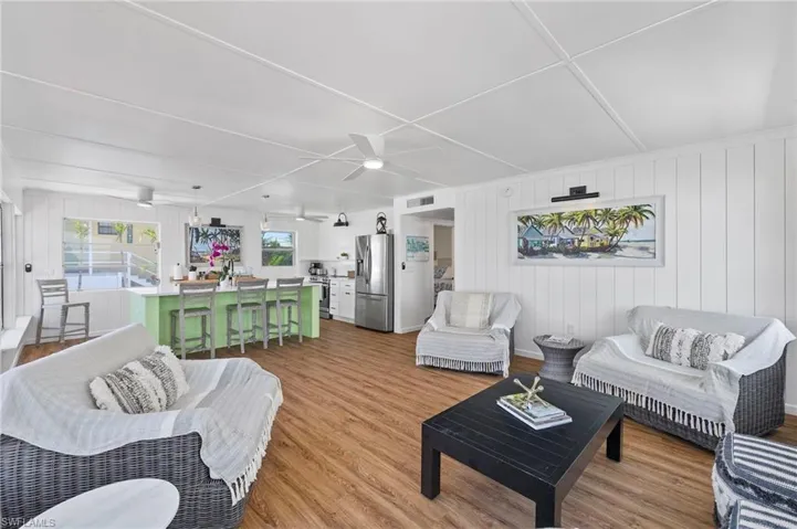 Living room with ceiling fan, wooden walls, and light hardwood / wood-style flooring