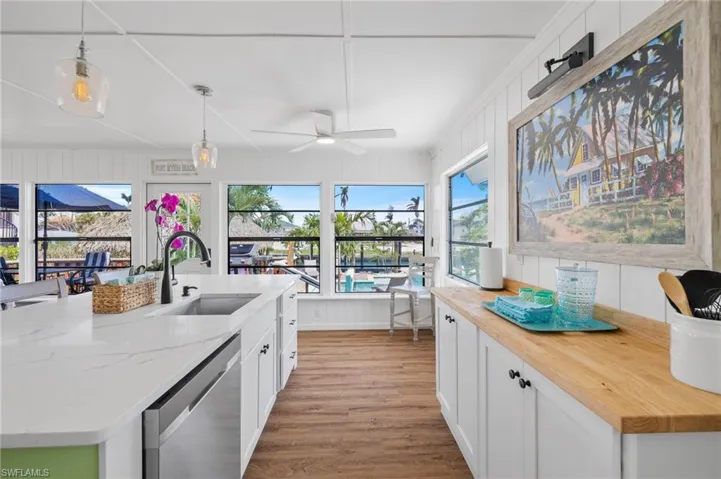Kitchen featuring pendant lighting, white cabinetry, stainless steel dishwasher, and sink