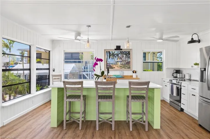 Kitchen featuring white cabinets, a kitchen bar, an island with sink, and appliances with stainless steel finishes