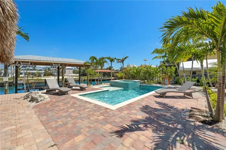 View of pool, Boat House, patio area, a water view, and an in ground hot tub