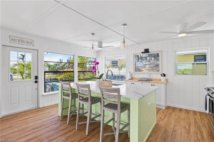 Kitchen with hanging light fixtures, ceiling fan, an island with sink, a kitchen bar, and white cabinetry