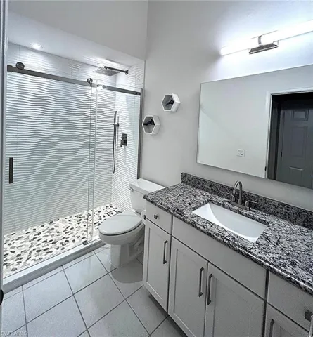 Full bathroom with vanity, light tile patterned flooring, and a stall shower