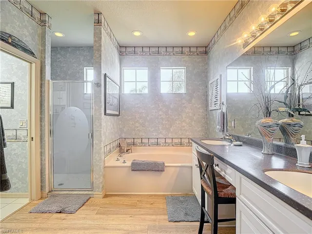Bathroom featuring wood-type flooring, separate shower and tub, and vanity