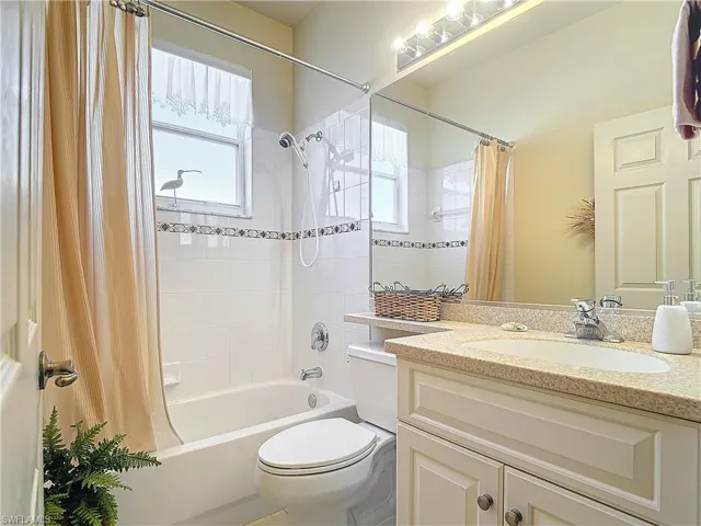 Full bathroom with vanity, shower / tub combo, and toilet