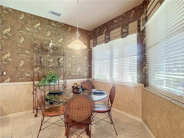 Dining space with a textured ceiling, tile patterned floors, and a wealth of natural light