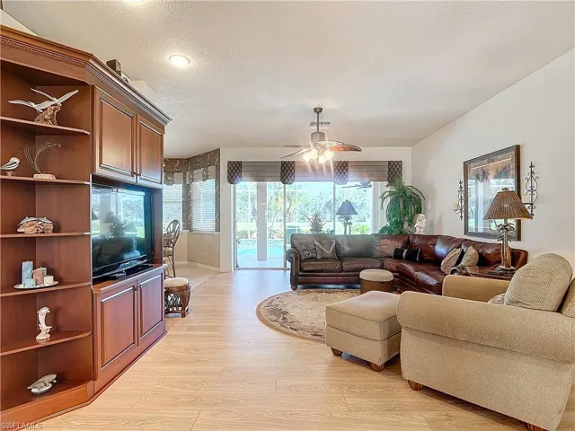 Living room featuring light wood-type flooring, ceiling fan, and a textured ceiling