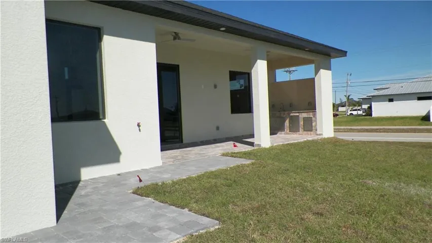 Doorway to property featuring a yard, a patio area, and stucco siding