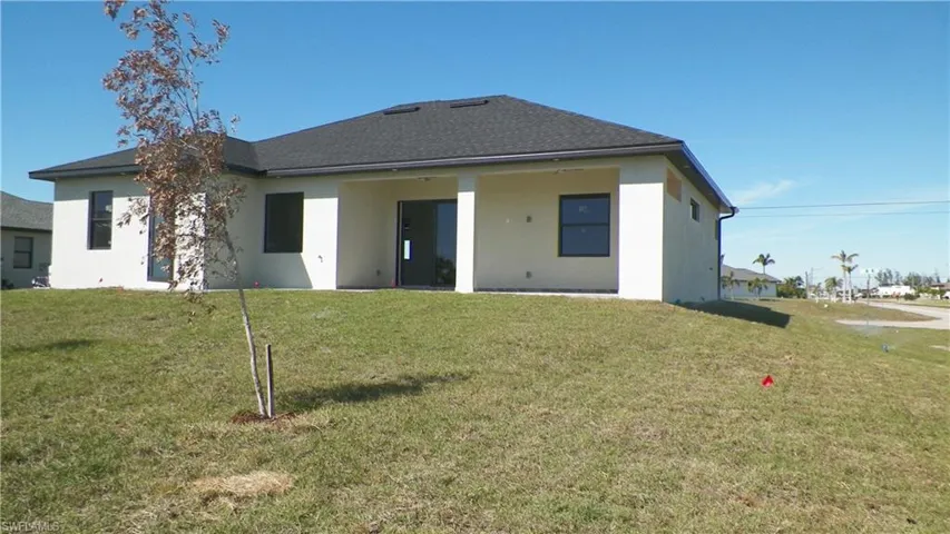 Rear view of property featuring stucco siding and a lawn