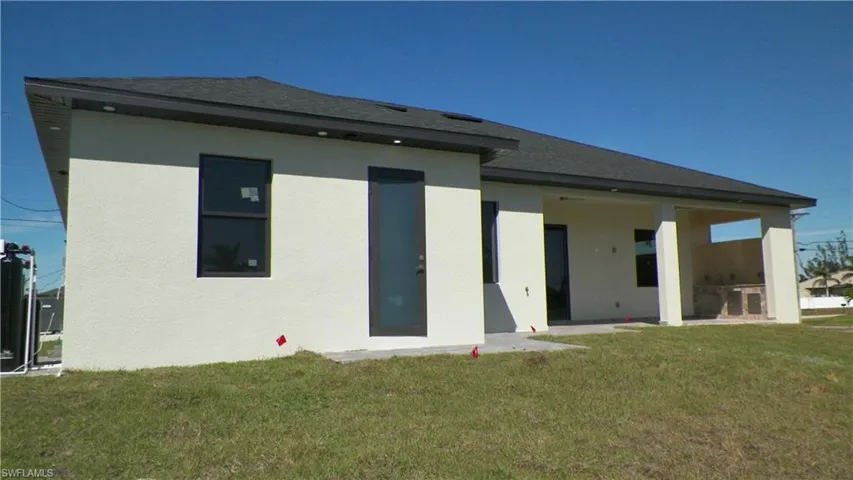 Back of property with a yard, roof with shingles, and stucco siding