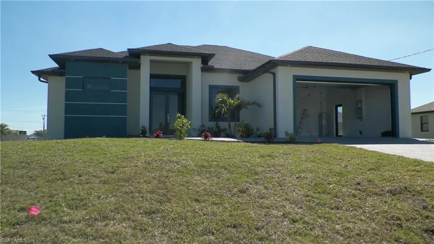 Prairie-style home featuring stucco siding, driveway, an attached garage, and a front lawn
