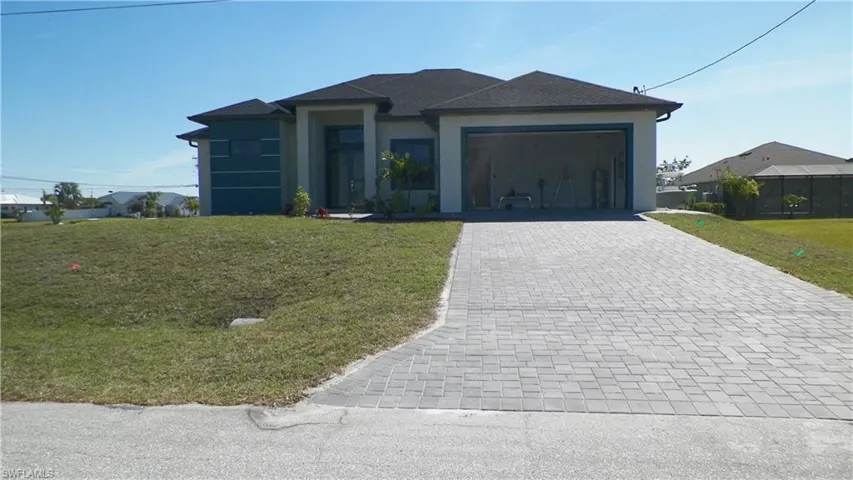 Prairie-style house featuring stucco siding, a front lawn, decorative driveway, and a garage