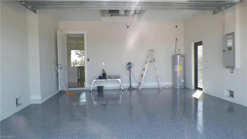 Garage with electric panel, baseboards, and electric water heater