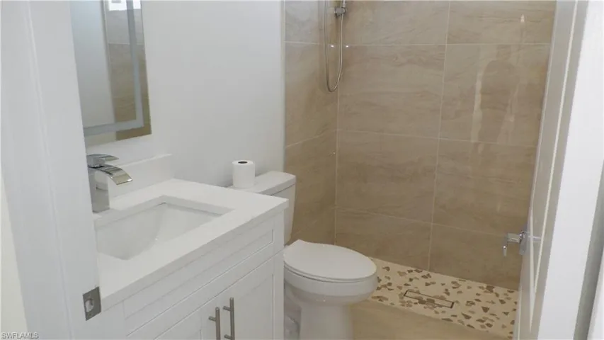 Full bath with vanity, toilet, and tiled shower