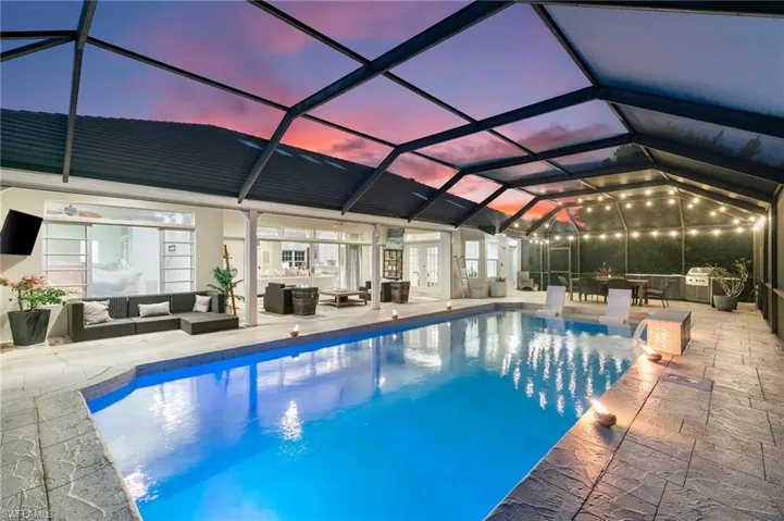 Pool at dusk featuring an outdoor living space, a patio, and a lanai