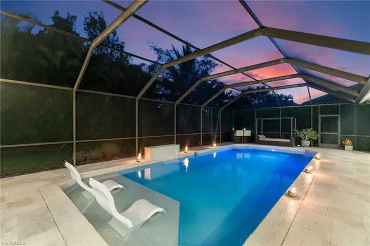 Pool at dusk featuring a patio and glass enclosure