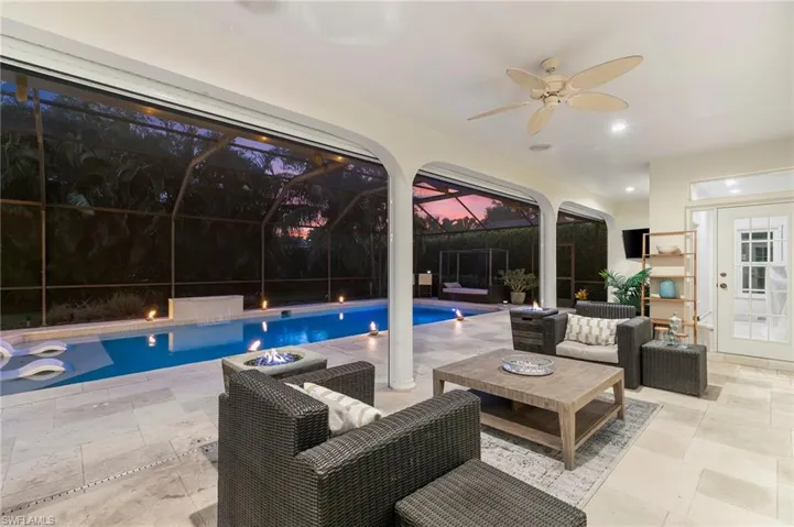 View of swimming pool with an outdoor living space, a patio area, glass enclosure, and ceiling fan
