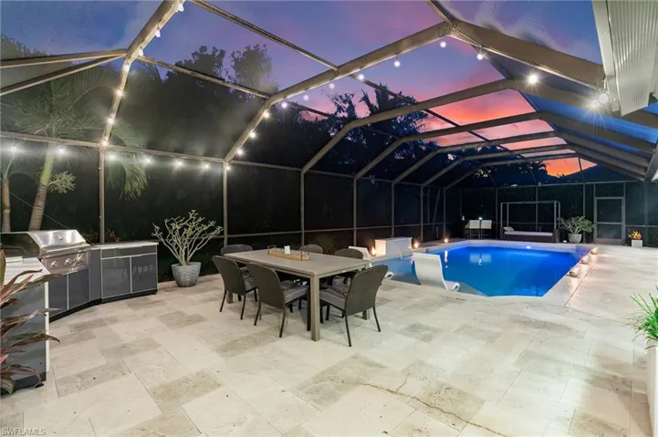 Pool at dusk featuring area for grilling, a patio, and a lanai