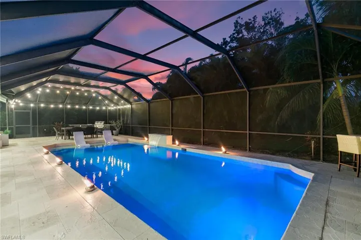 Pool at dusk with a patio and a lanai
