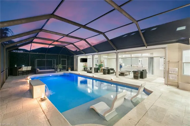 Pool at dusk featuring a patio, an outdoor living space, pool water feature, and a lanai