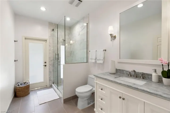 Bathroom featuring vanity, toilet, tile patterned floors, and a shower with door