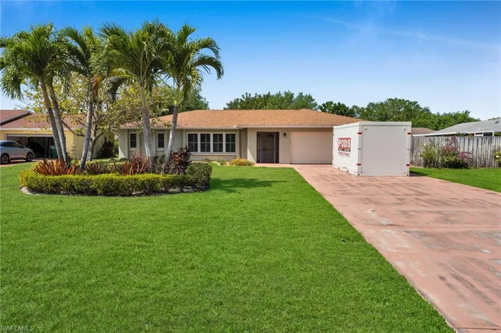 Ranch-style house with concrete driveway, a garage, a front yard, and stucco siding