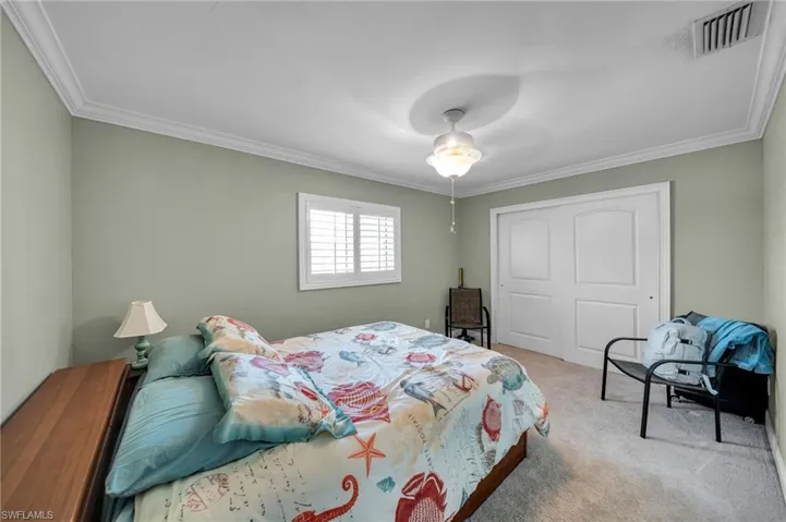 Bedroom with a closet, visible vents, carpet floors, and ornamental molding