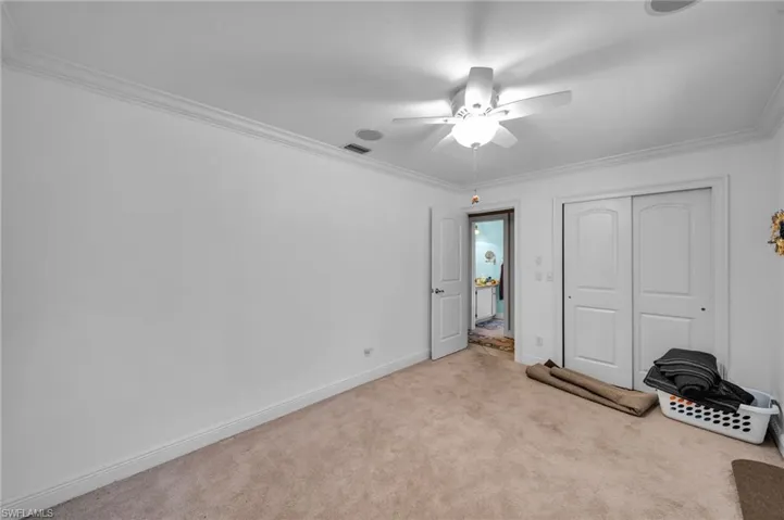 Unfurnished bedroom featuring visible vents, ornamental molding, a closet, carpet floors, and baseboards
