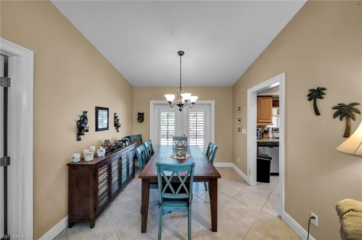 Dining space with an inviting chandelier, light tile patterned floors, baseboards, and vaulted ceiling