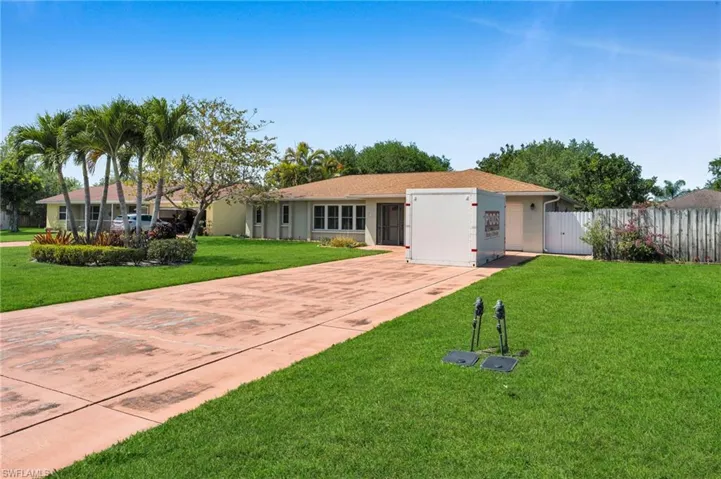 Ranch-style house with stucco siding, driveway, a front lawn, and fence