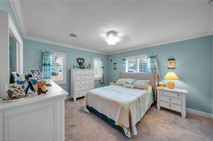 Bedroom with ornamental molding, baseboards, and light carpet