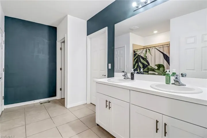 Bathroom featuring dual bowl vanity and tile patterned flooring
