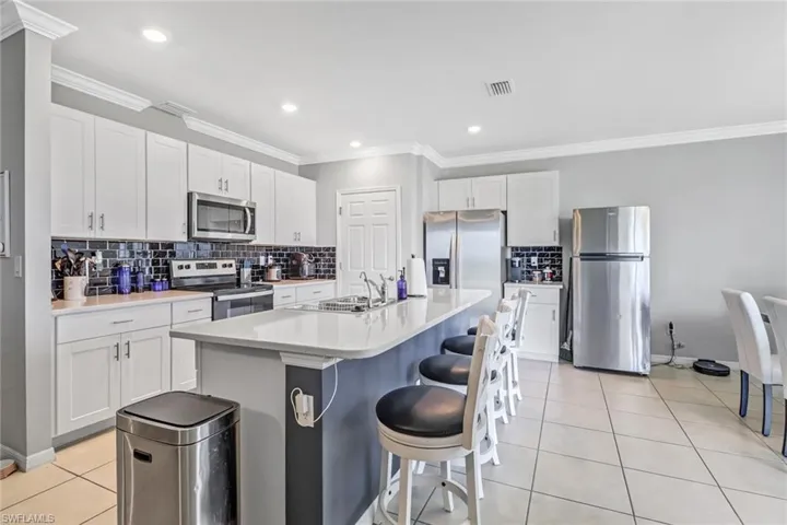 Kitchen featuring tasteful backsplash, an island with sink, stainless steel appliances, and sink