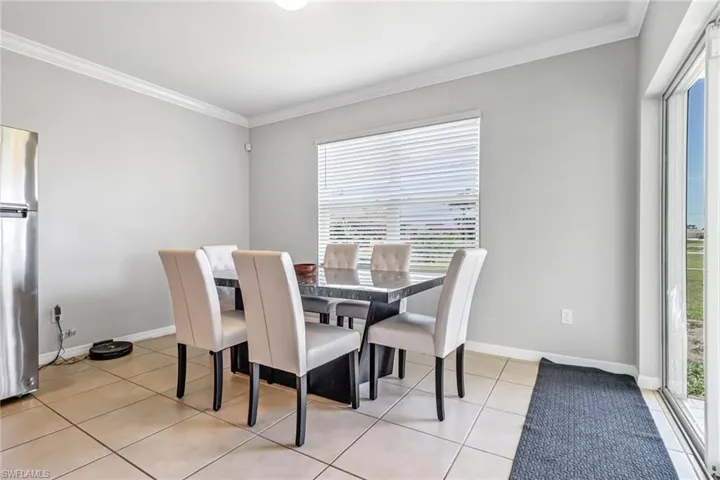 Dining room with light tile patterned flooring and ornamental molding