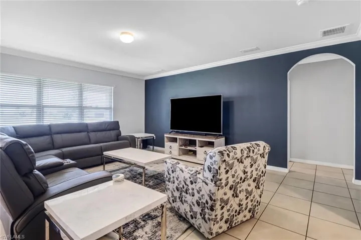 Living room with crown molding and light tile patterned floors