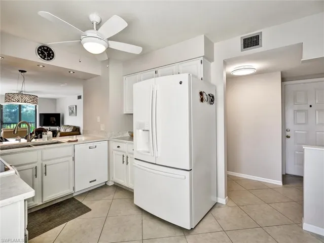 Kitchen featuring white cabinets, white appliances, light countertops, light tile patterned floors, and ceiling fan