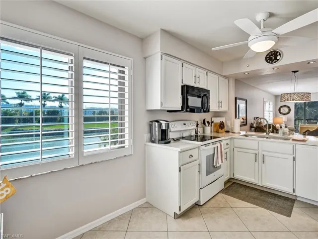 Kitchen featuring white appliances, white cabinets, ceiling fan, hanging light fixtures, and light countertops