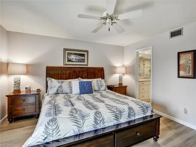 Bedroom with connected bathroom, light wood-style floors, and ceiling fan
