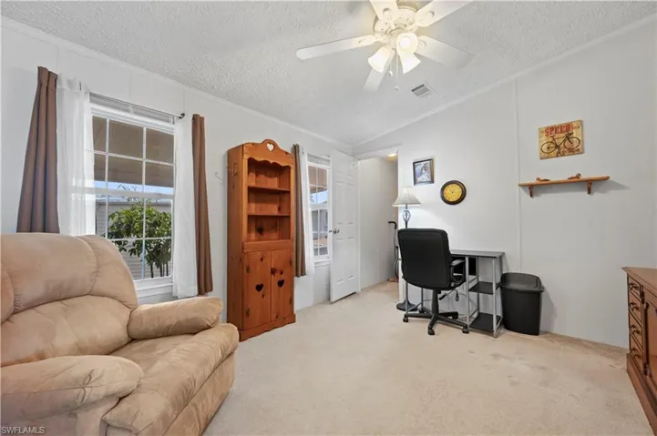Office space with ceiling fan, vaulted ceiling, a textured ceiling, and light colored carpet
