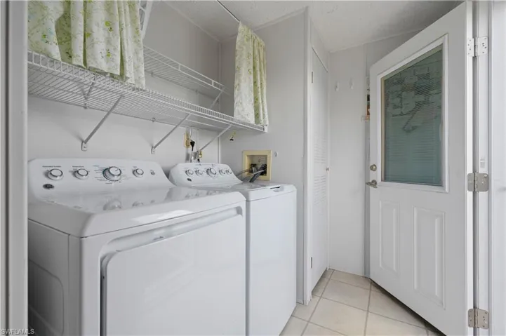Laundry area featuring washing machine and dryer, hookup for a washing machine, a textured ceiling, and light tile floors