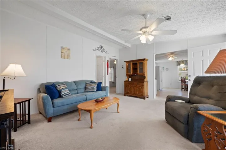 Living room featuring a textured ceiling, carpet floors, and ceiling fan