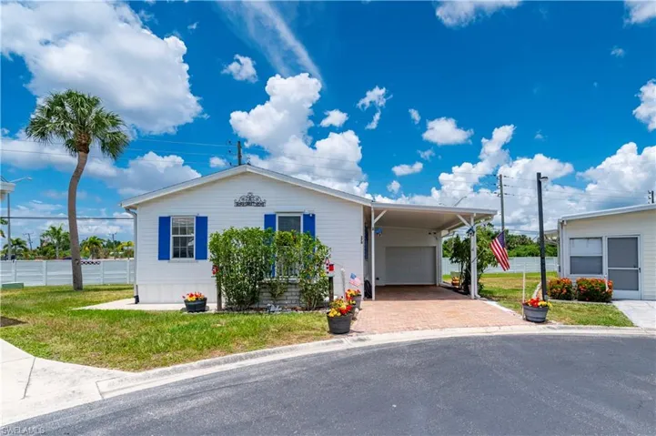 View of front of property with a carport, a garage, and a front yard